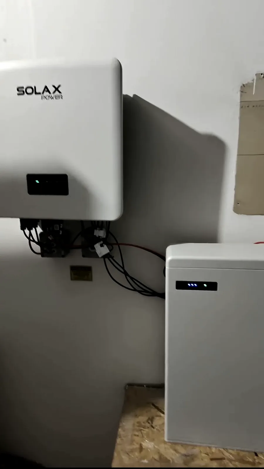 Inversor híbrido instalado na parede, com cabeamento organizado descendo para o quadro