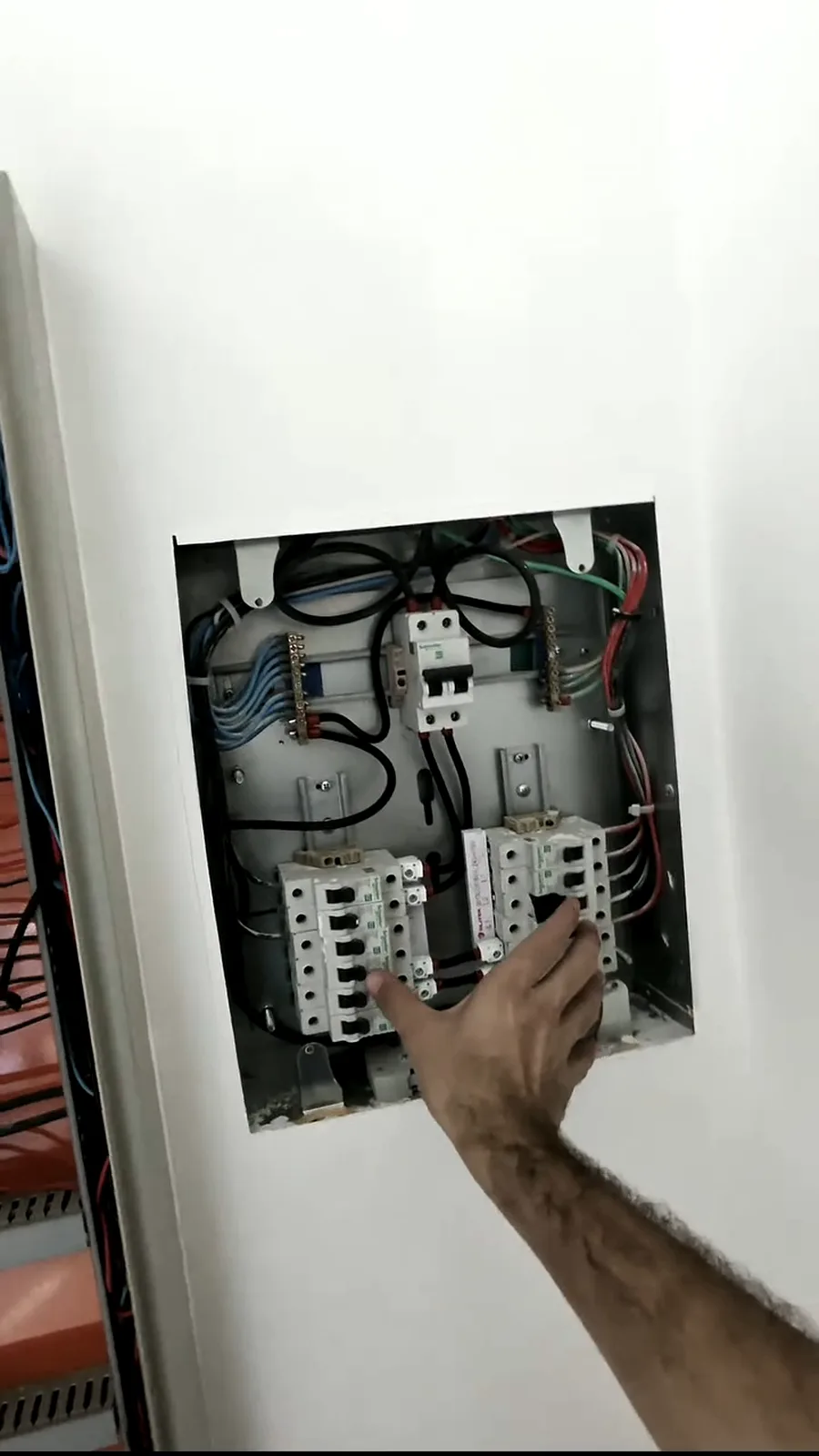 Quadro elétrico aberto durante a instalação, com técnico trabalhando nos disjuntores