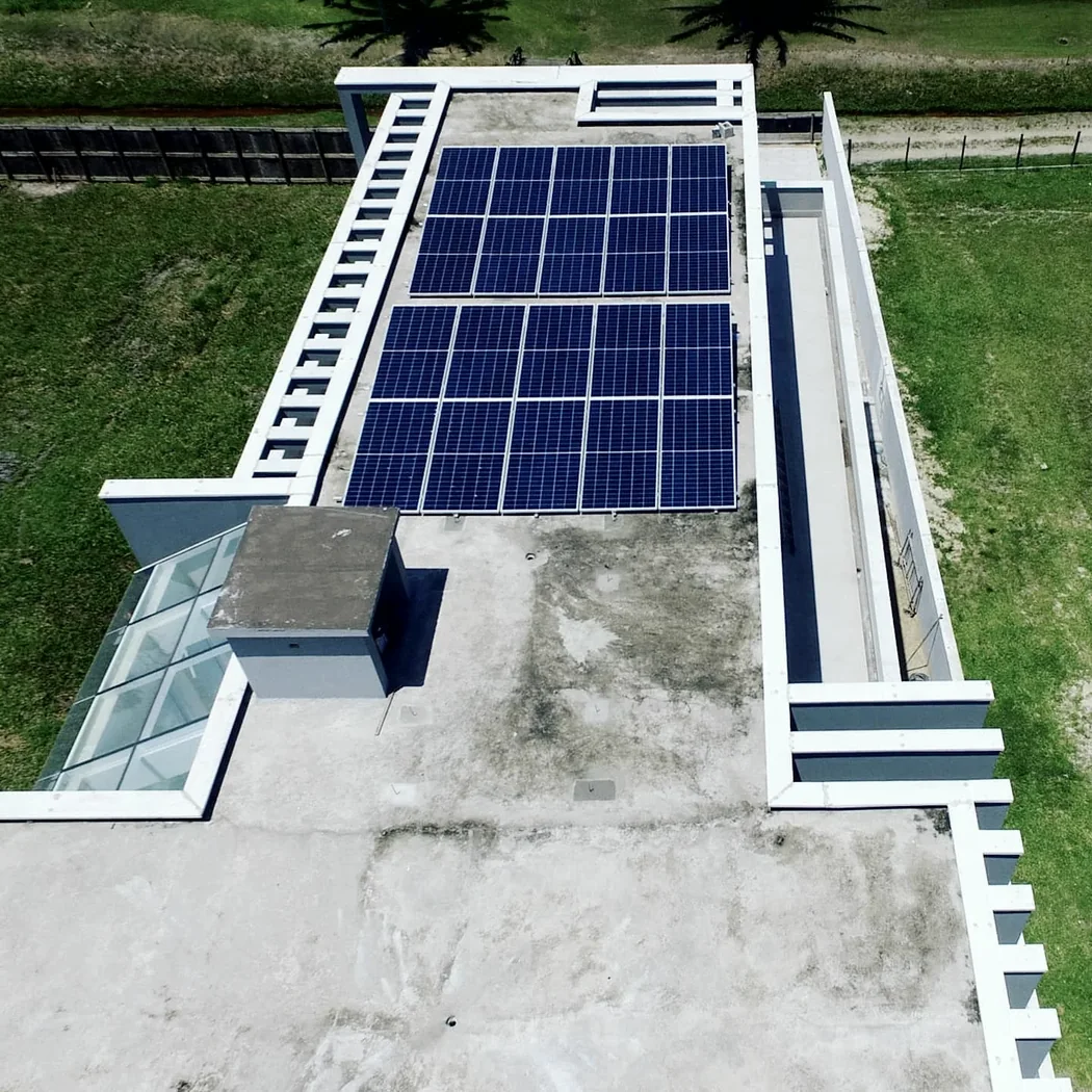 Módulos fotovoltaicos instalados sobre laje de uma residência moderna, com piscina ao lado