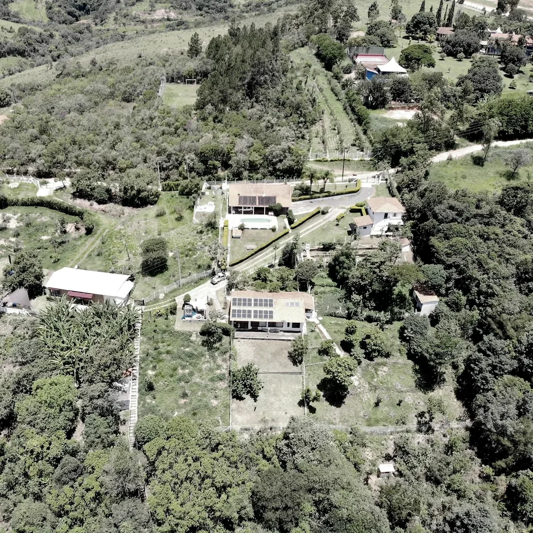 Vista aérea de área rural com construções, vegetação e estrutura de geração instalada