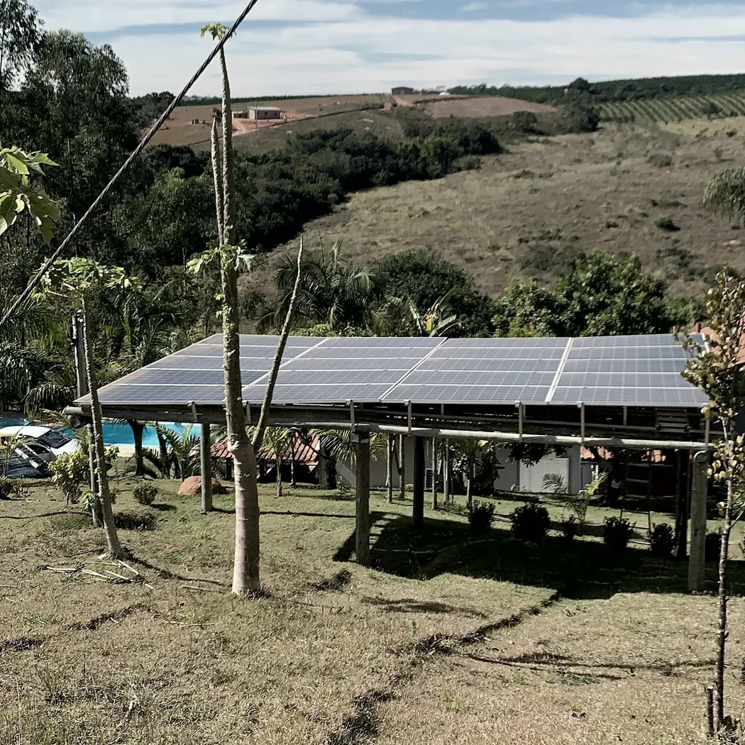 Estrutura de cobertura com módulos fotovoltaicos instalada sobre área aberta em propriedade rural