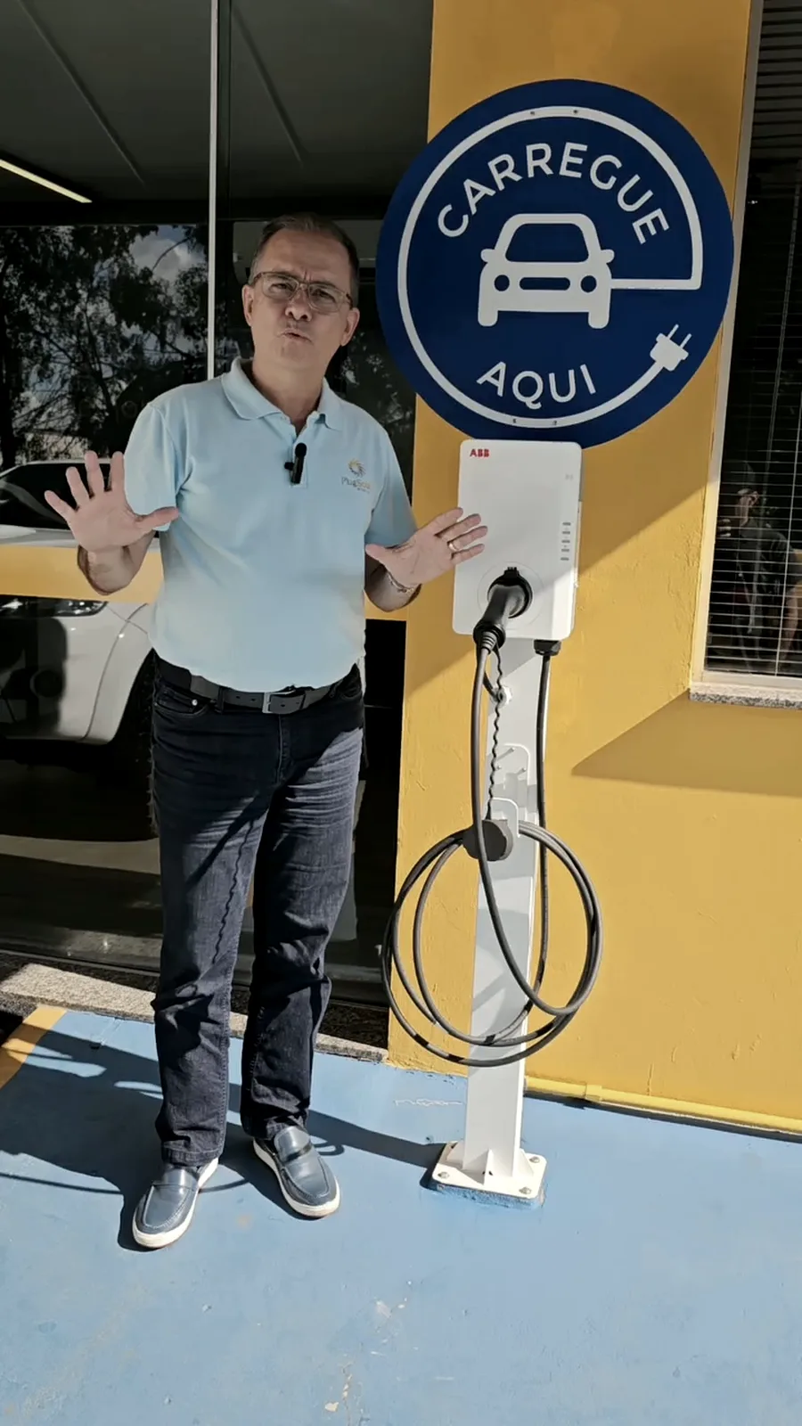 Profissional da Plug Solar ao lado de estação de recarga instalada na entrada da sede da empresa