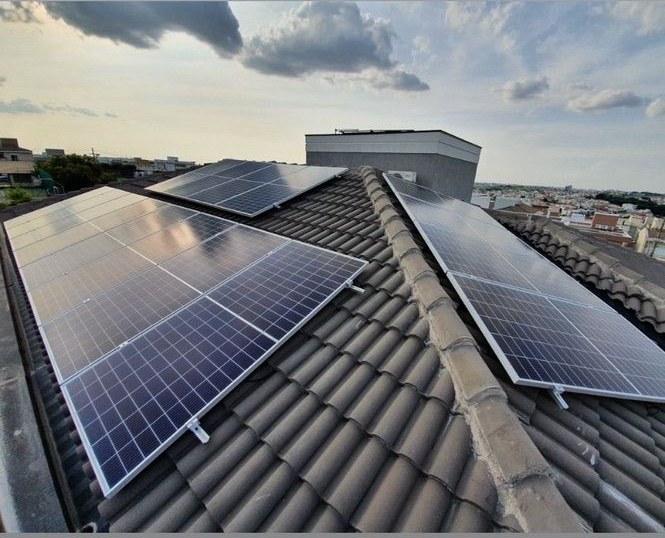 Detalhe aproximado dos módulos fotovoltaicos e da estrutura de fixação sobre o telhado
