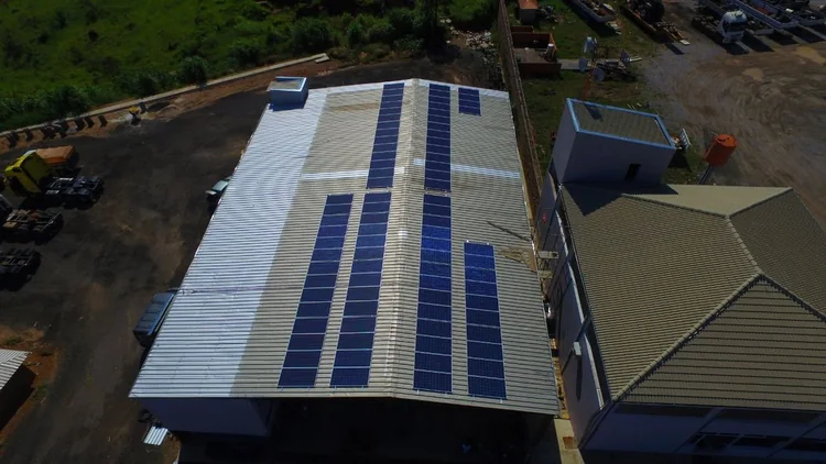 Telhado metálico industrial com estrutura de fixação e módulos fotovoltaicos instalados em fileiras