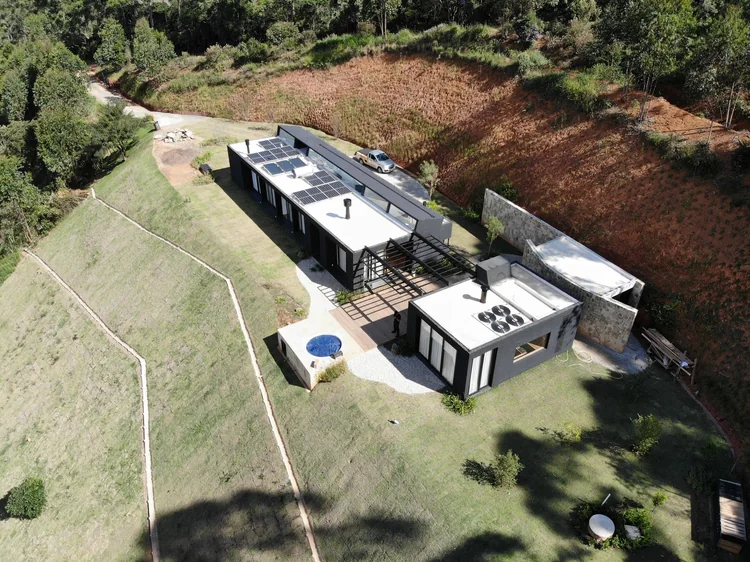 Vista aérea de residência moderna em terreno com desnível, com piscina e módulos fotovoltaicos instalados na cobertura