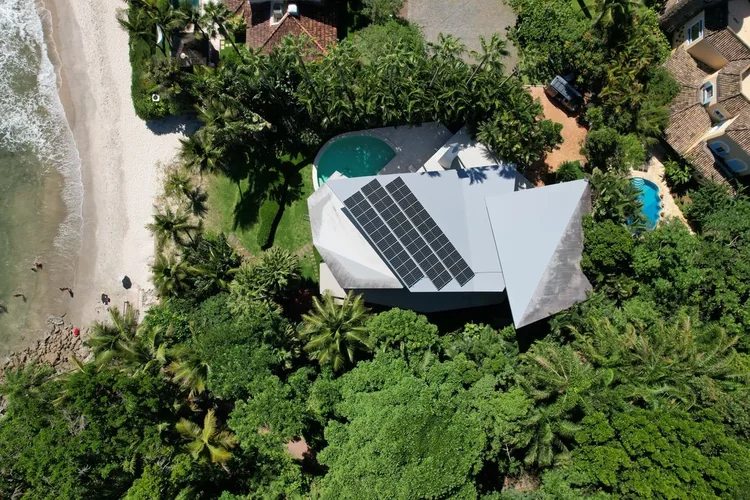 Casa de praia de alto padrão com sistema fotovoltaico ocupando a face de maior insolação do telhado